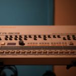 Close-up of a classic Roland TR-909 drum machine in a studio setting.