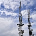 Wireless Energy Transfer: The Future of Operational Leverage Telecommunication towers with antennas and dishes under a bright cloudy sky.